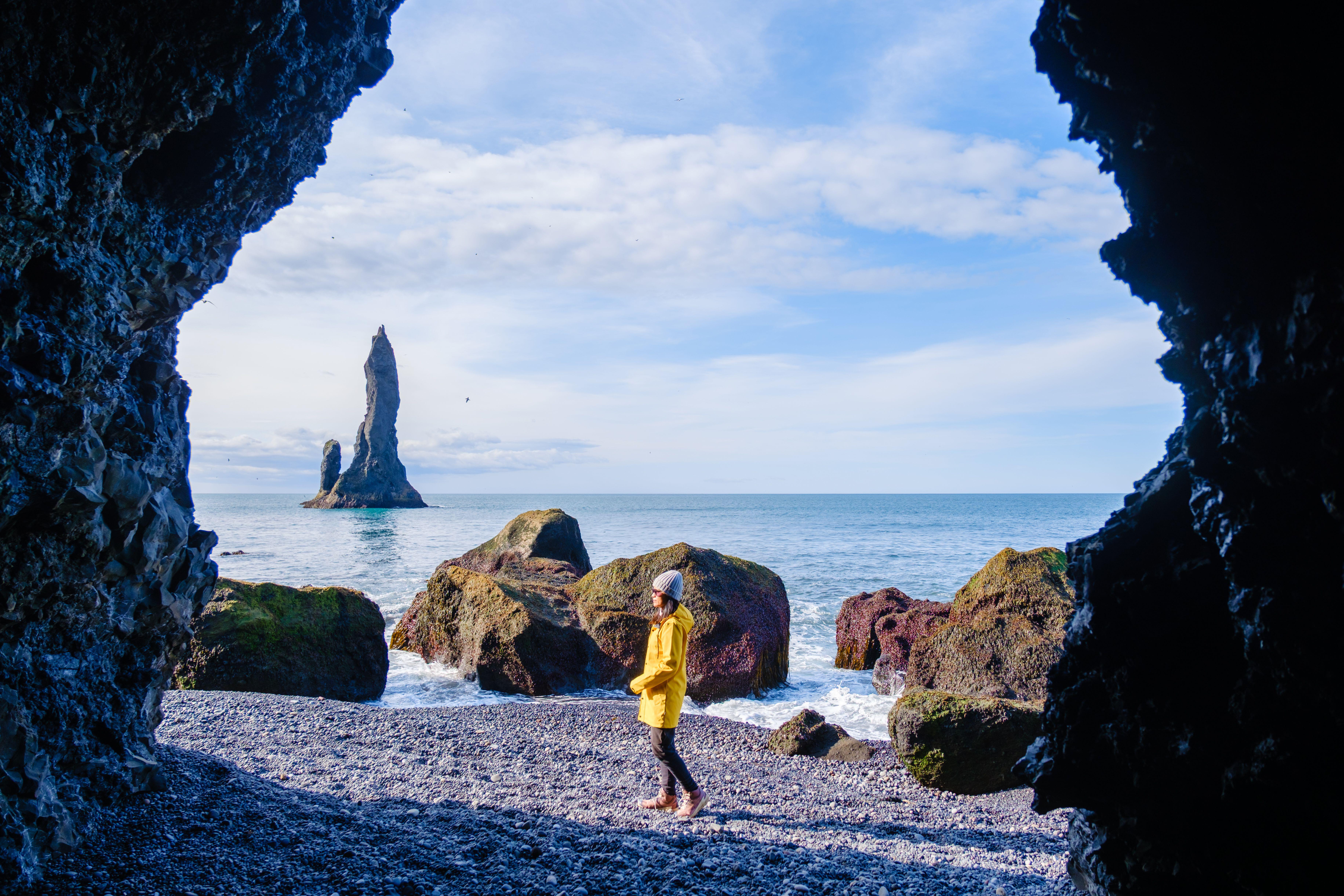 A traveller in a yellow jacket on Reynisfjara beach in Iceland
