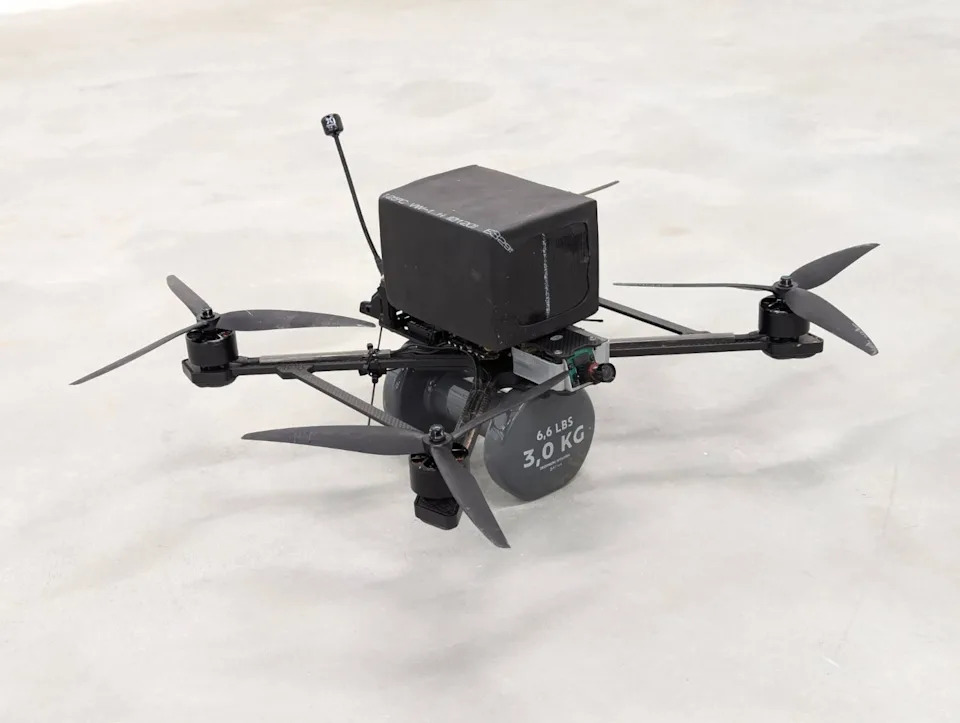 A small black drone with a six-pound grey dumbbell