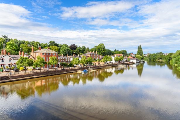 Residential buildings along a riverside street under blue sky with clouds on a summer day. Chester, England, UK.