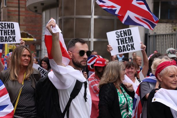 People who were protesting against asylum seekers were standing with Union Jack and St George's Cross flags. Some people had sheets of paper with the words "Send them Back" printed on them