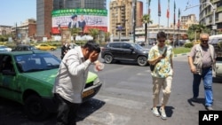 An Iranian taxi driver cools down by splashing water on his head on a street amid soaring temperatures in Tehran on July 22