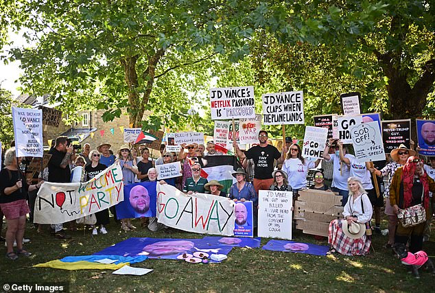 Protesters pose with banners and placards during a 'Vance not welcome party' organised by Stop Trump Coalition in Charlbury, Oxfordshire, on August 12