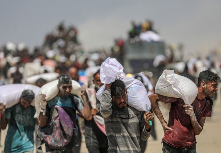 epaselect epa12290446 Internally displaced Palestinians carry bags of flour near a food distribution point in Zikim, northern Gaza Strip, 08 August 2025. Humanitarian organizations have warned of an imminent food catastrophe for thousands of children, a crisis caused by severe food insecurity, a decline in health services, and ongoing restrictions on humanitarian aid and essential supplies. EPA/MOHAMMED SABER