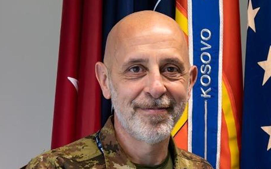 Rodolfo Sganga poses for a portrait in front of flags.