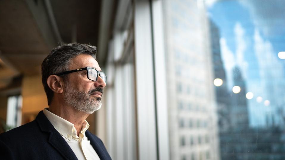 Mature businessman looking out of window contemplating tariff strategies