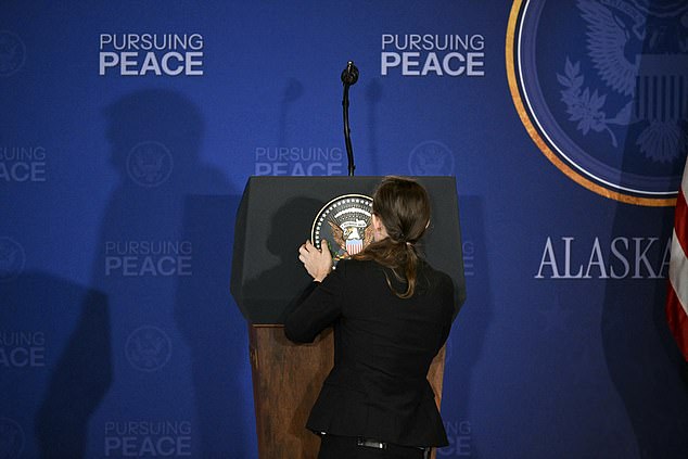 A staff member adjusts the presidential seal ahead of a US-Russia summit on Ukraine with US President Donald Trump and Russian President Vladimir Putin at Joint Base Elmendorf-Richardson in Anchorage, Alaska, on August 15, 2025. (Photo by Drew ANGERER / AFP) (Photo by DREW ANGERER/AFP via Getty Images)