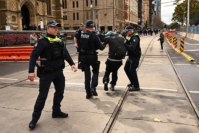 epa12338728 Victoria Police remove a man as protestors gather outside Flinders Street Station during the March for Australia anti-immigration rally in Melbourne, Sunday, August 31, 2025.  EPA/JOEL CARRETT  AUSTRALIA AND NEW ZEALAND OUT