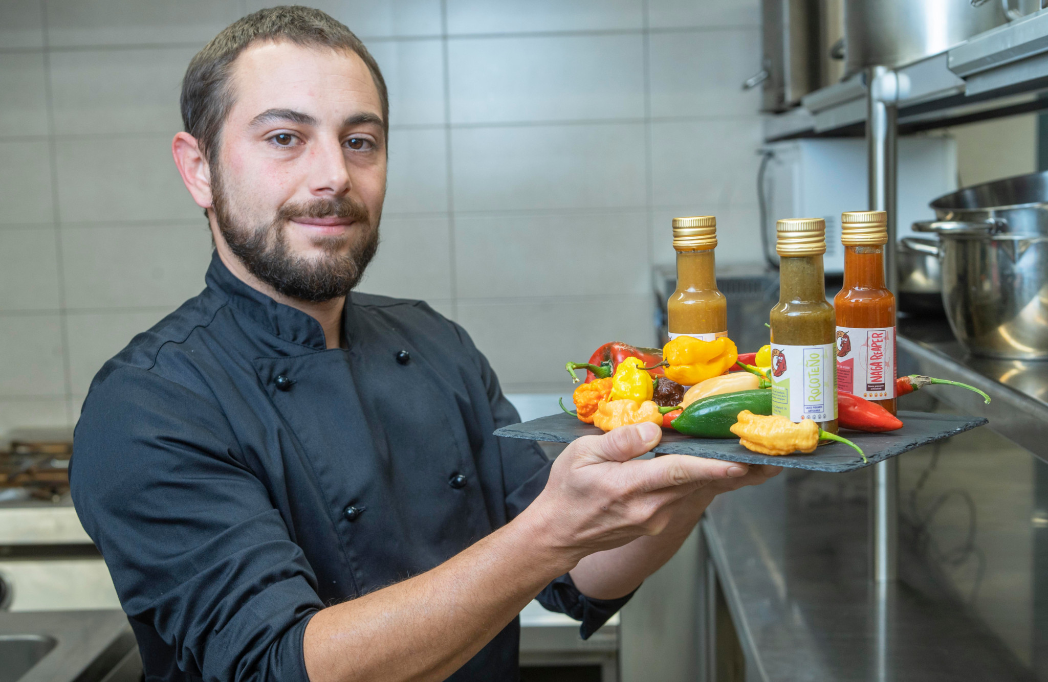 Lucas Malacari présente des piments bio et des sauces piquantes artisanales dans une cuisine à Echallens.