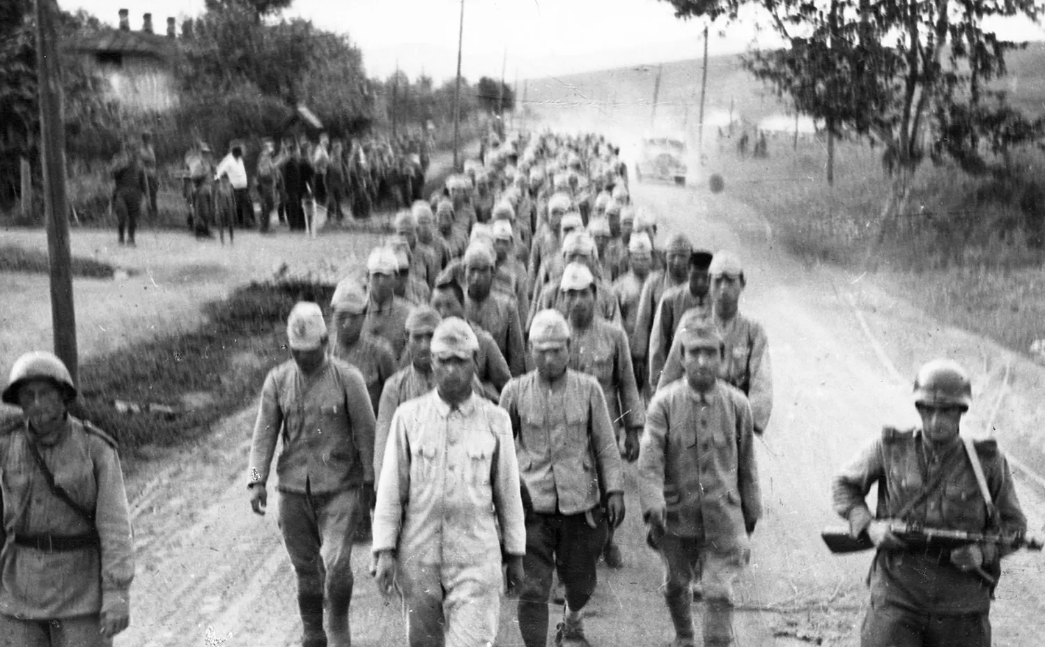 Rows of people in uniforms walk down a road