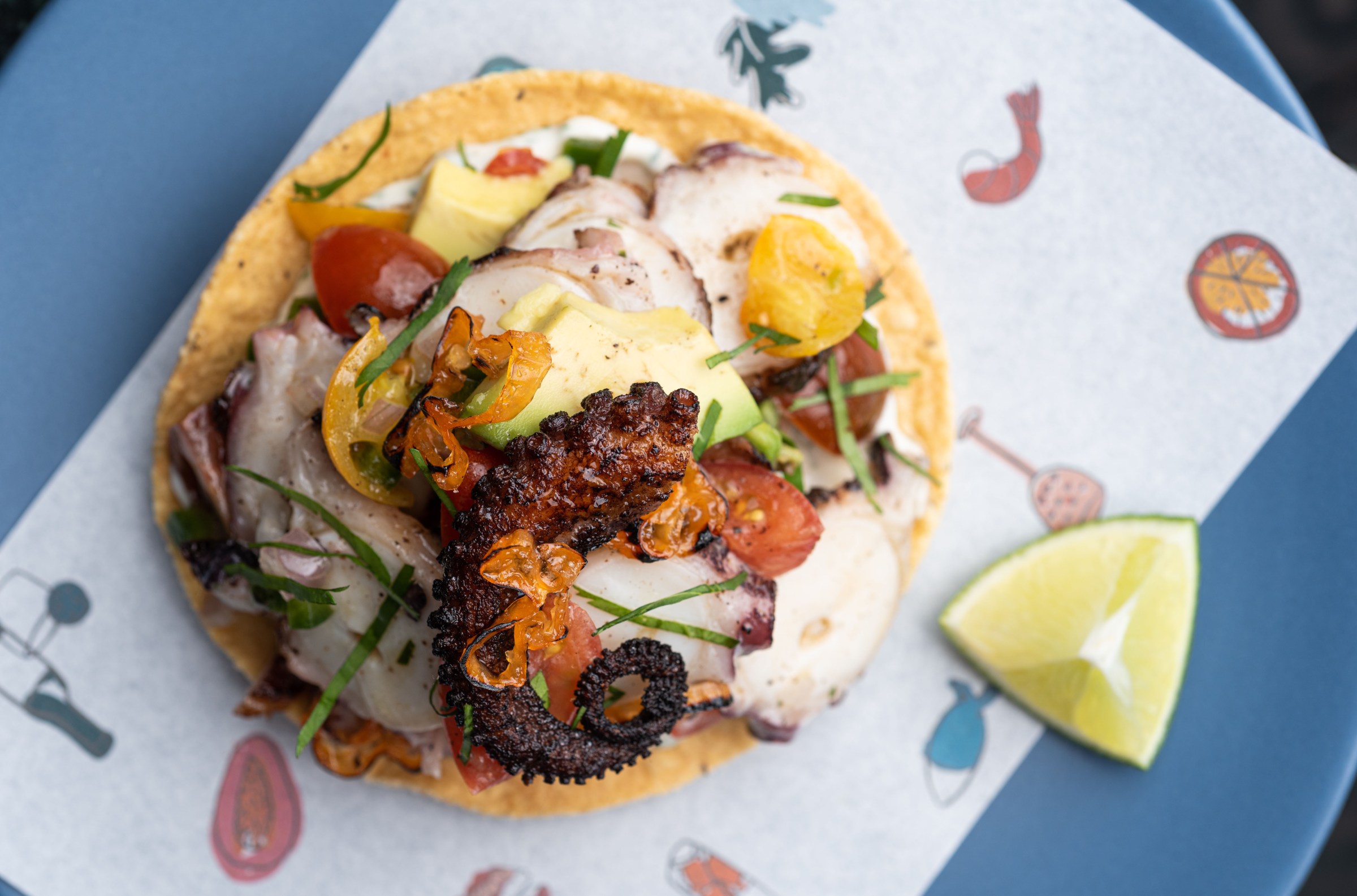 Octopus tostada with a paper backing.
