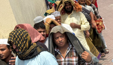 People cover their heads with prayer mats for shade following Friday prayers, during the summer heat in Dubai