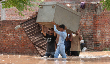 Residents carry their belongings to a safer place as they move through a water-logged residential area located on the bank...