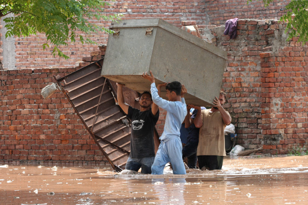 Residents carry their belongings to a safer place as they move through a water-logged residential area located on the bank...