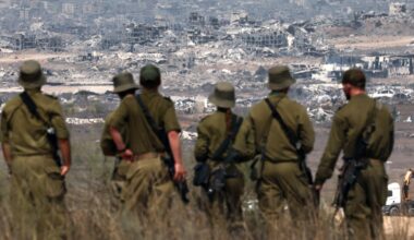 Israeli soldiers look at destroyed buildings in the Gaza Strip as they stand on the border with the Palestinian territory, on August 13, 2025.