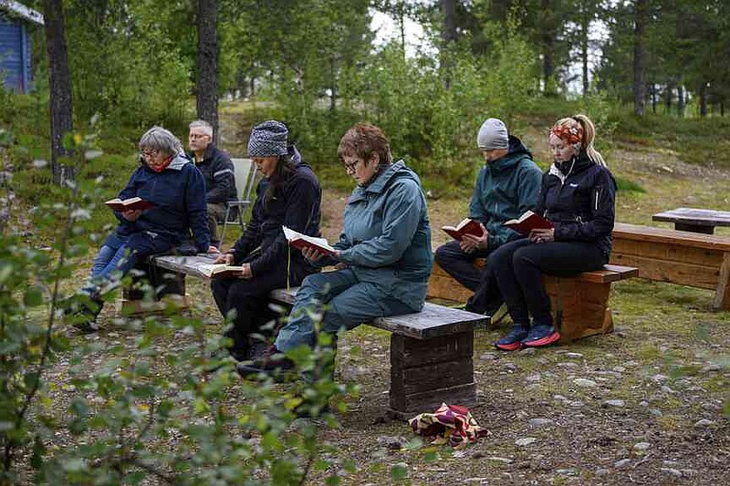 People hold an outdoor prayer for the move of the Kiruna Church, a Sami style wooden Swedish Lutheran church, called Kiruna Kyrka in Swedish, in Kiruna, Sweden, Sunday, Aug. 17, 2025, two days before its move along a 5-kilometer (3-mile) route east to a new city center as part of the town's relocation. (AP Photo/Malin Haarala)