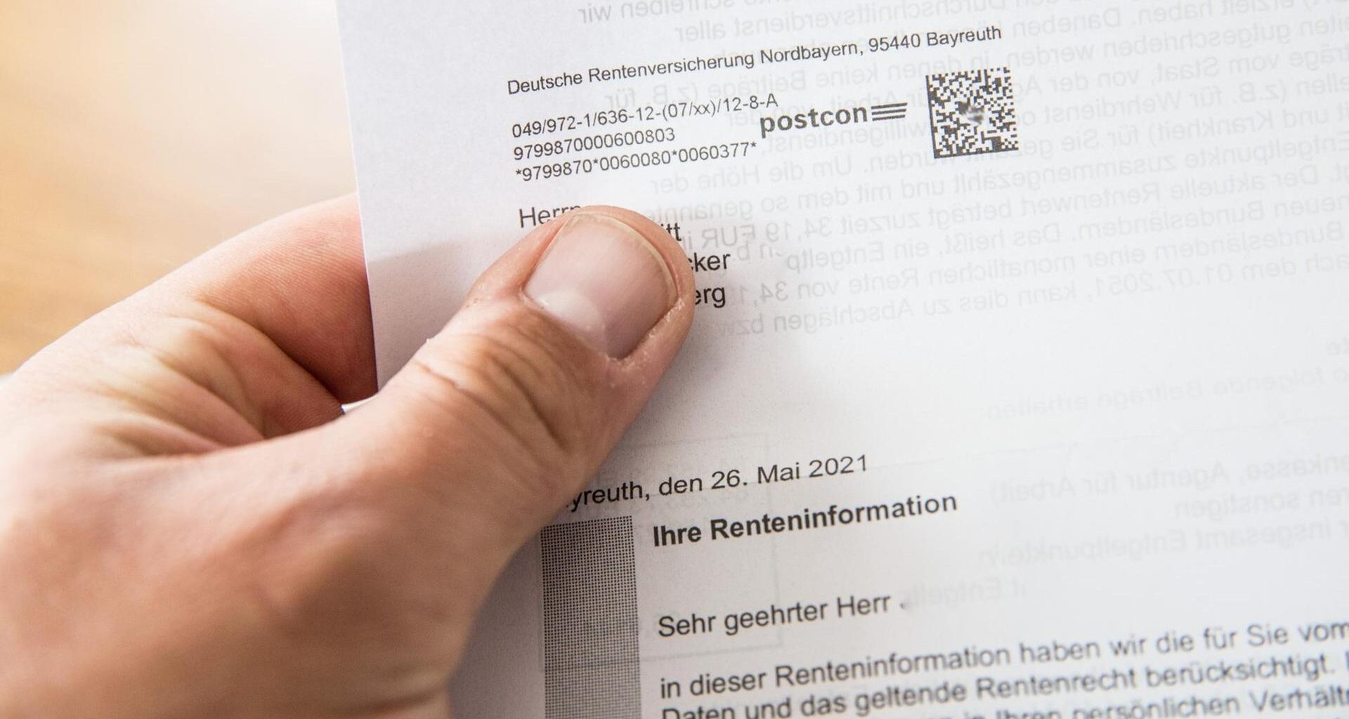 Eine Person hält einen Rentenbescheid der Deutschen Rentenversicherung in der Hand