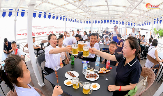 Visitors at North Korea's Wonsan-Kalma coastal tourist area drink beer in this picture published by the Rodong Sinmun on July 24. [NEWS1] 