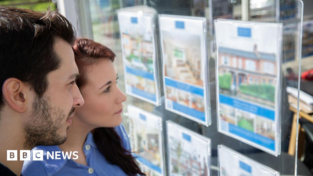 Homebuyers look at an estate agents window display - stock shot