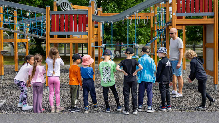 Photo shows kids in a playground.