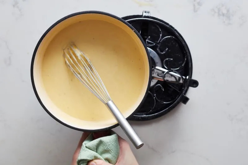 someone is putting the cooked cheese fondue on the fondue burner