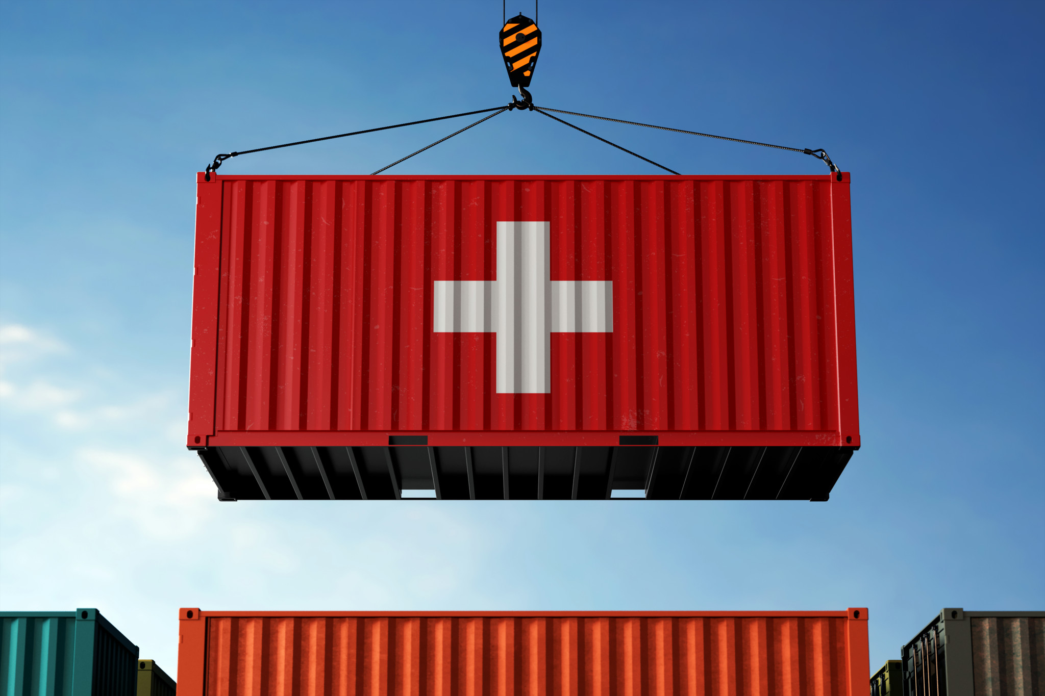 Schweizer Frachtcontainer mit Landesflagge hängt vor einem wolkigen Himmel.