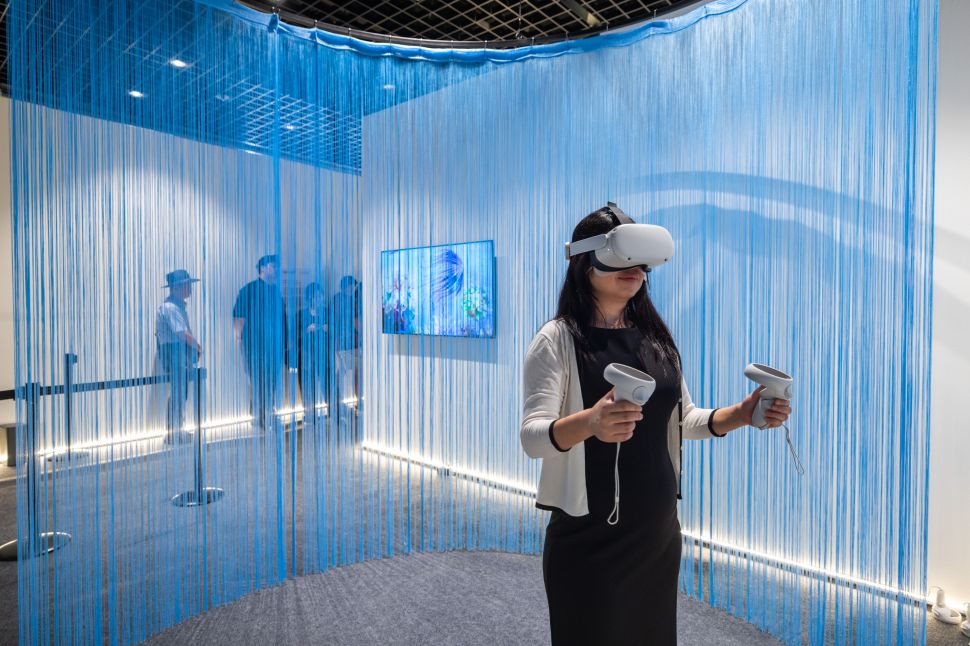 Woman explores a virtual reality art installation behind blue cords.