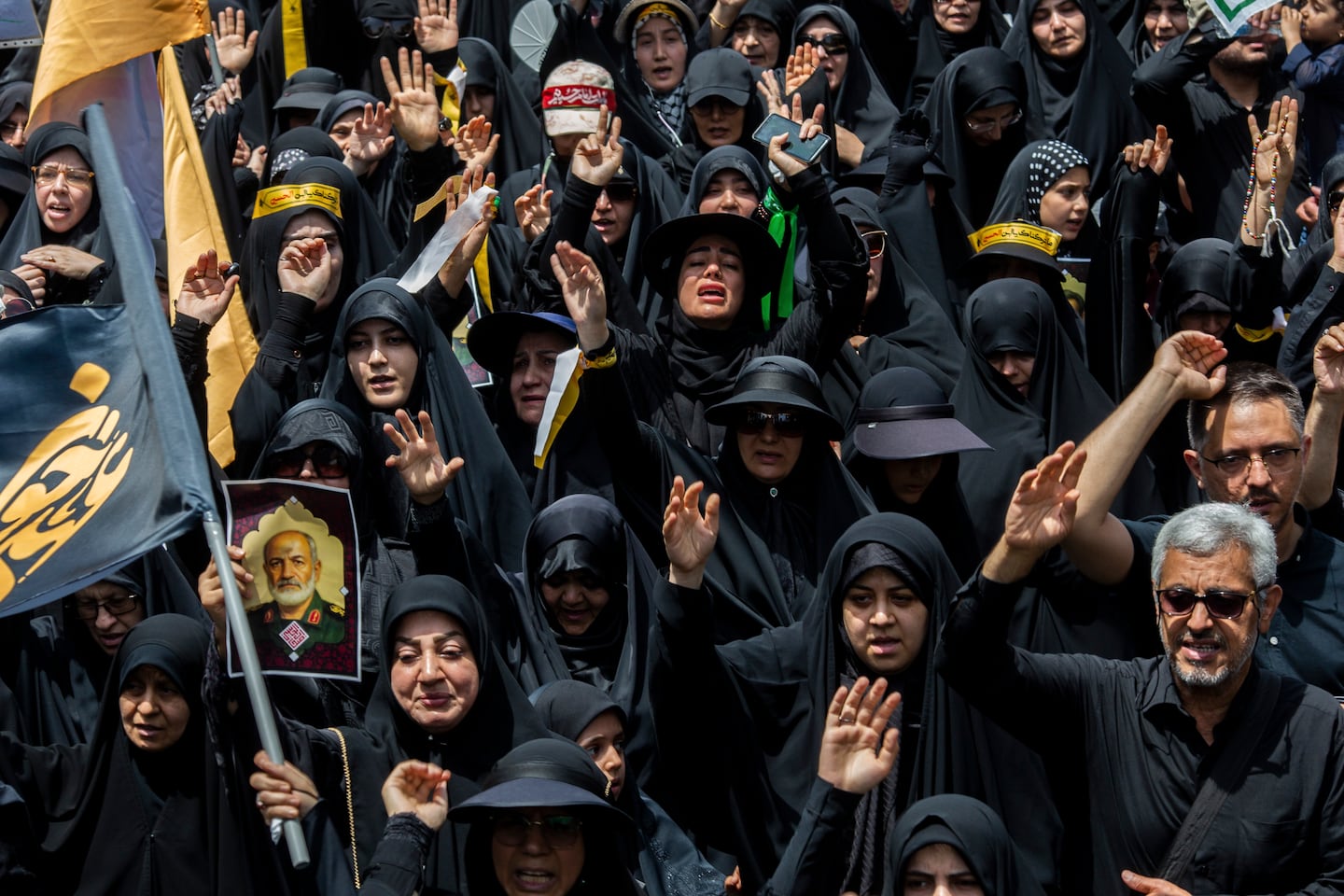 Iranians, including one holding an image of a general killed in an Israeli attack, march during a Tasua ceremony, a day for Shia Muslims of mourning and commemoration of martyrdom, in Tehran on July 5.