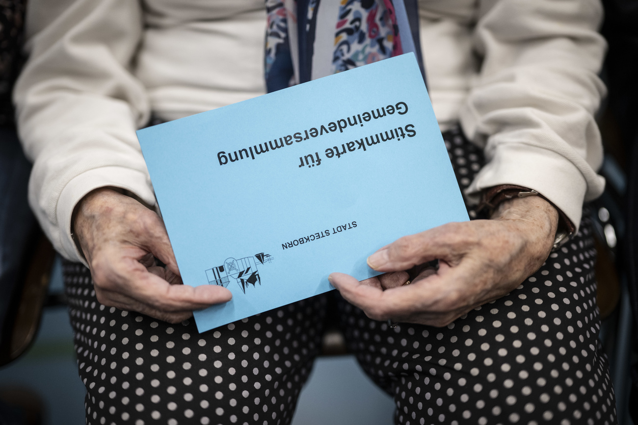 Eine Stimmbuergerin haelt ihre Stimmrechtskarte in der Gemeindeversammlung, aufgenommen am Donnerstag, 15. Februar 2024, in Steckborn. Die Gemeinde entscheidet heute an einer ausserordentlichen Versammlung ueber die Kuendigung des Vertrages mit dem Staatssekretariat fuer Migration SEM. Die Anlage im Wohnquartier ist umstritten. (KEYSTONE/Gian Ehrenzeller)