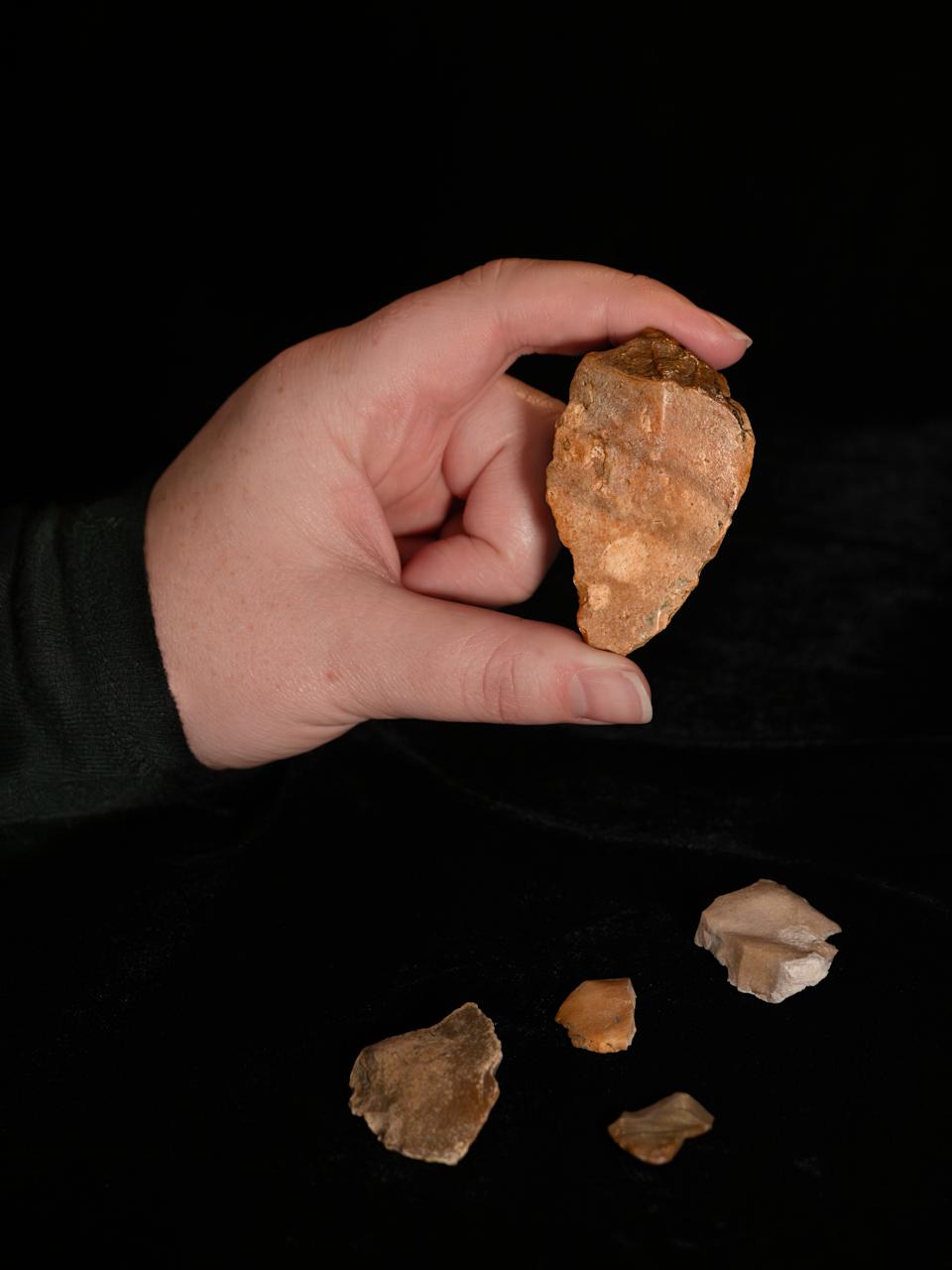 A human hand holding one of the tools. Several others are on the ground beneath it.