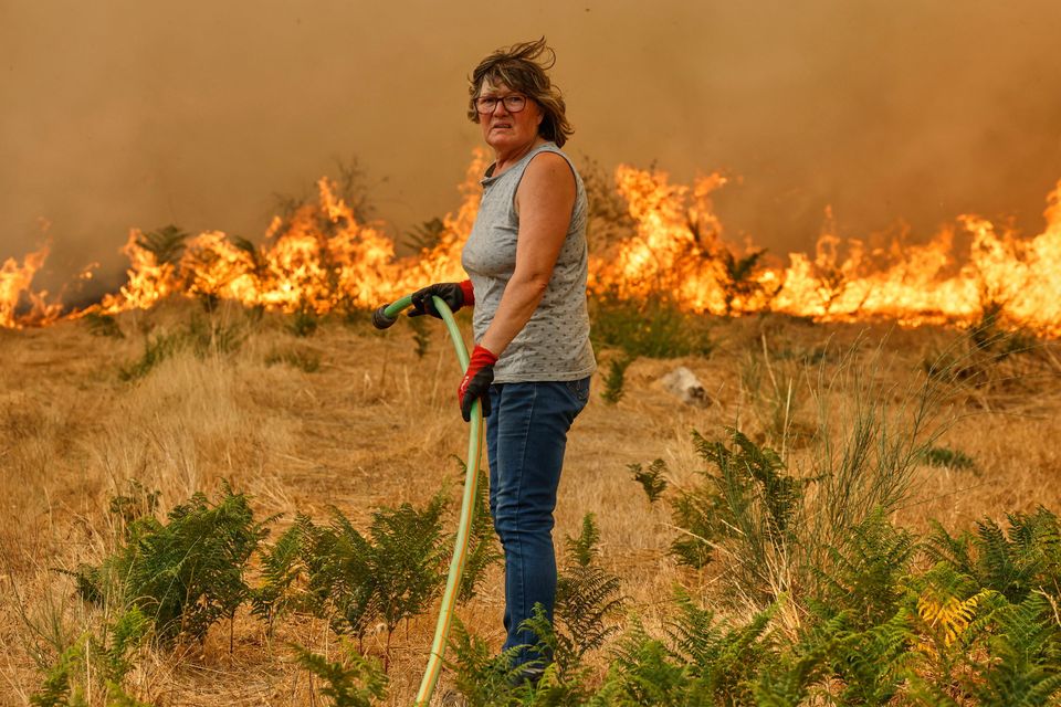 A woman with a hose tries to put out the fire during a wildfire in Santa Baia De Montes, northwestern Spain. Photo: Lalo R Villar/AP