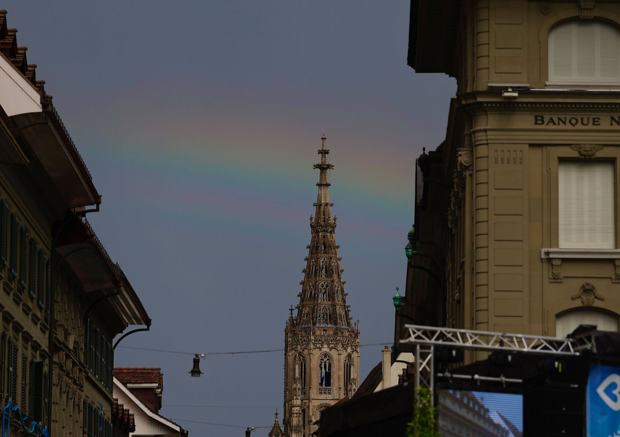 Regenbogen über dem Berner Münster, umgeben von historischen Gebäuden in einer Stadtstrasse. Regenbogen über dem Berner Münster, umgeben von historischen Gebäuden in einer Stadtstrasse.