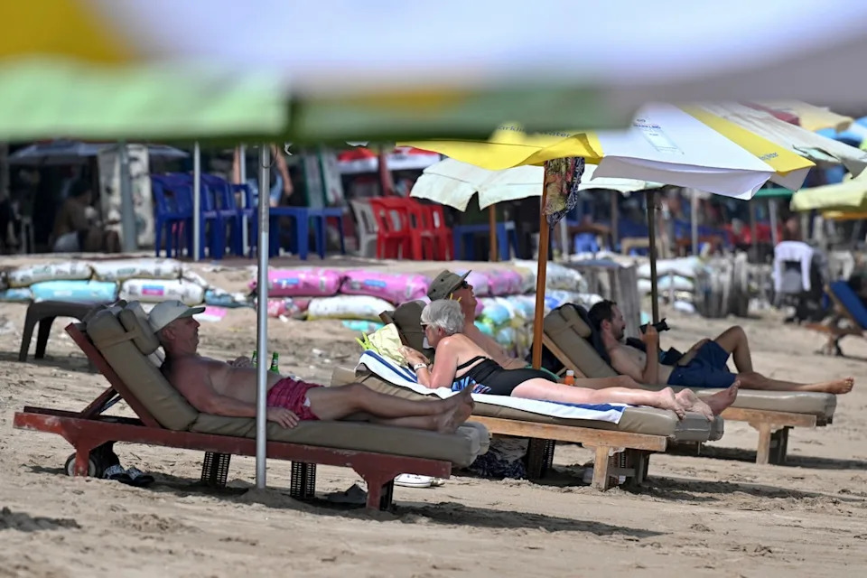 Tourists lie on beach chairs at Kuta Beach in Kuta near Denpasar on Indonesia's resort island of Bali on 27 May 2025 (AFP via Getty Images)