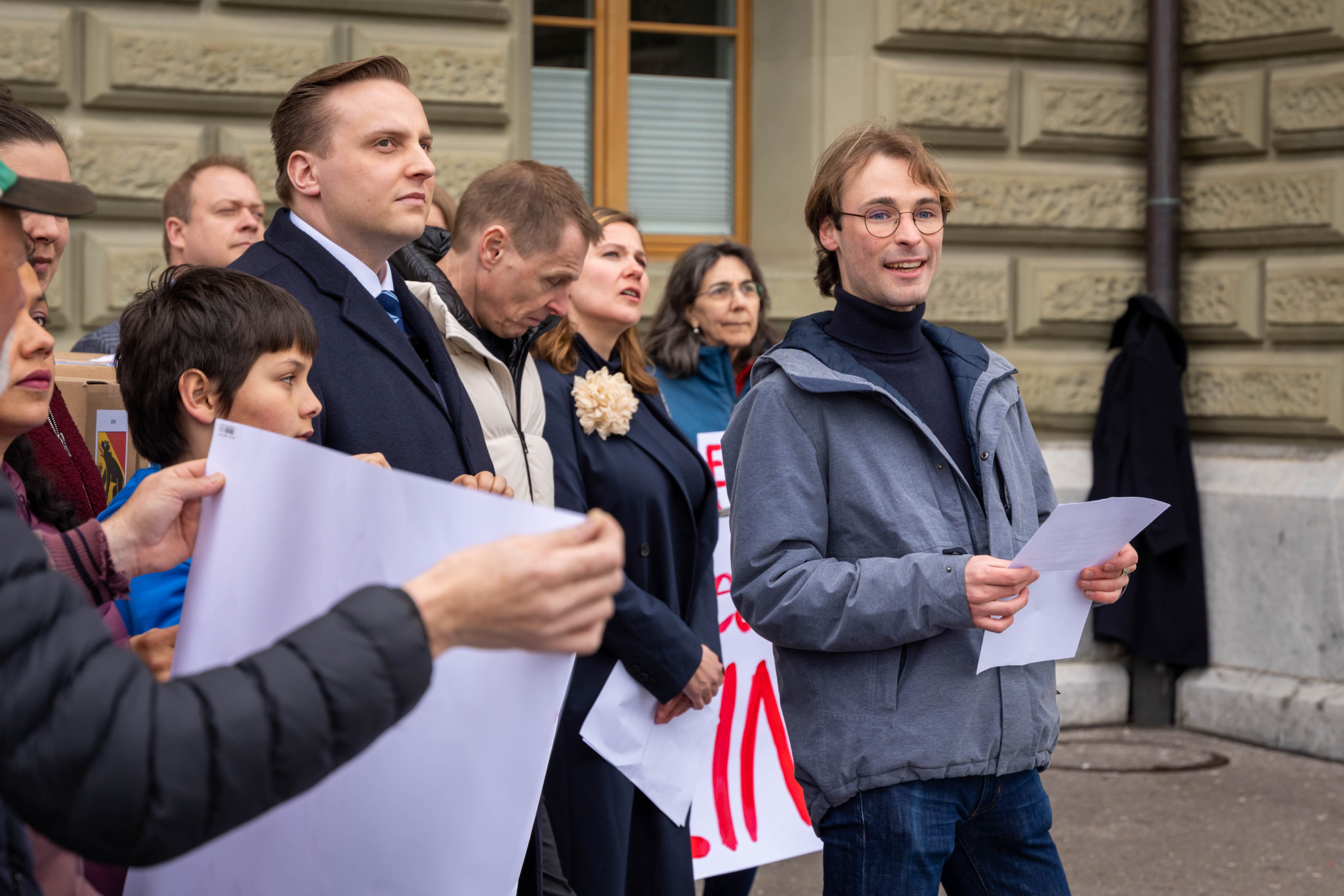 Jonas Sulzer, Kampagnenchef, bei der Unterschriftenabgabe gegen das E-ID Gesetz vor dem Bundeshaus in Bern am 17. April 2025, umgeben von weiteren Personen und Plakaten.