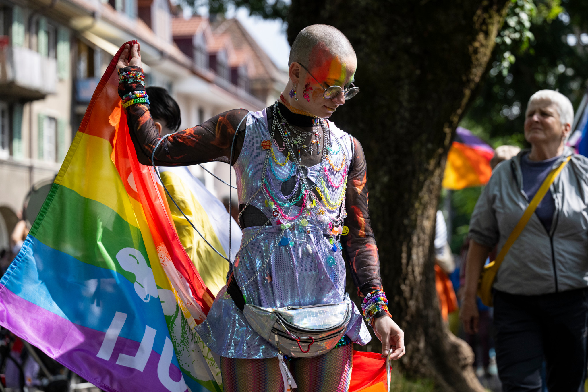 Person mit Regenbogen-Flagge und buntem Gesichtsschmuck bei der BernPride 2025 in Bern. Person mit Regenbogen-Flagge und buntem Gesichtsschmuck bei der BernPride 2025 in Bern.