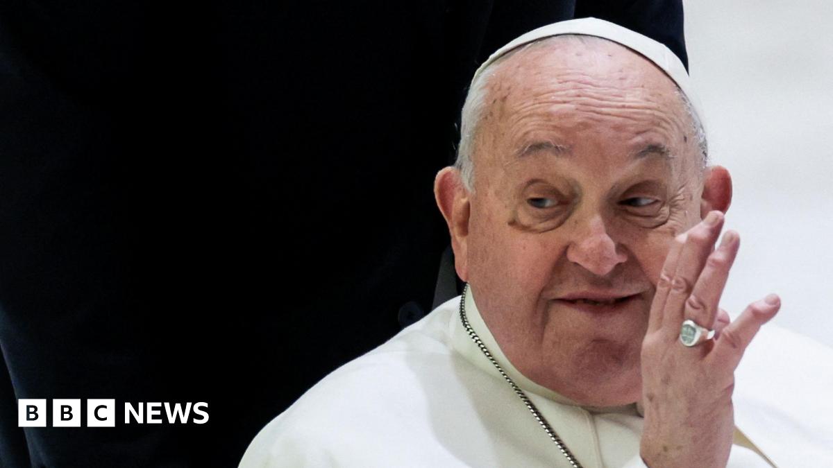 Pope Francis waving his left hand against a black and white background