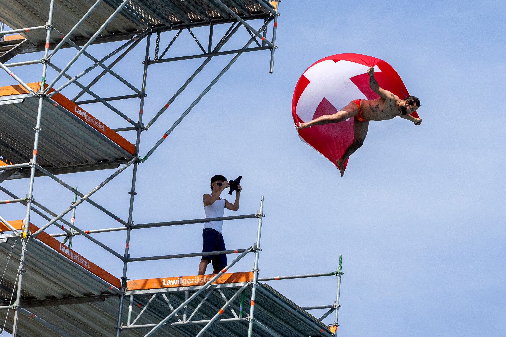Un plongeur effectue un saut spectaculaire avec une voile aux couleurs de la Suisse, lors du Lancy Cliff Diving à la piscine de Marignac à Genève.