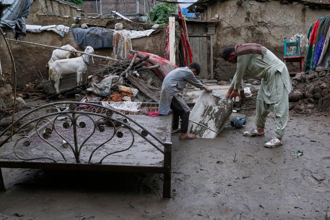 A father and his son retrieve a washing machine from the mud of their house, partially destroyed by the sudden floods that struck the village of Pir Baba, in Buner district, northwestern Pakistan, on Sunday, August 17, 2025.