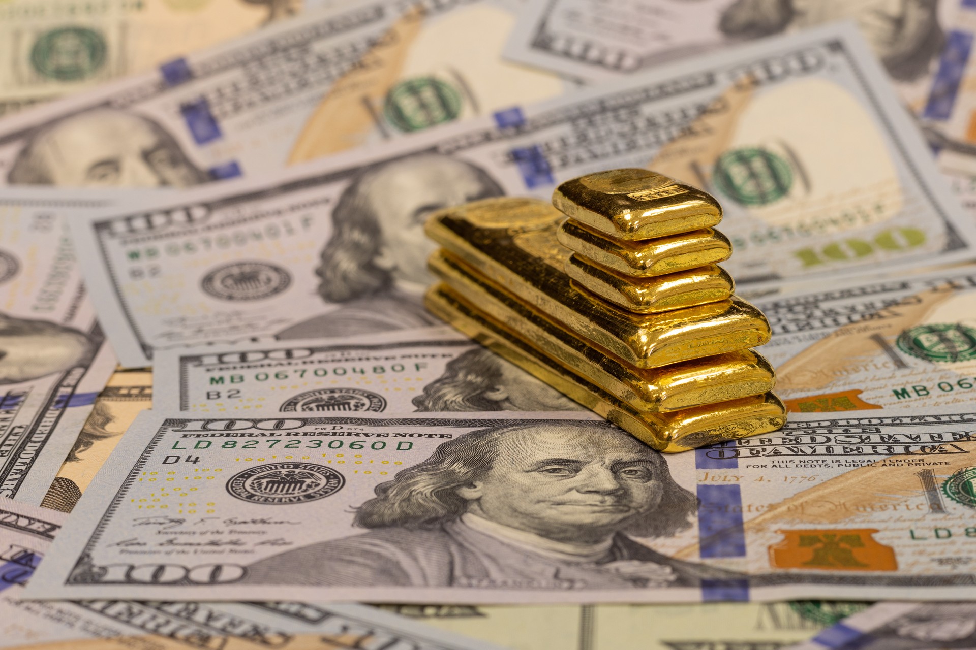 Photo illustration shows gold bars stacked on U.S. hundred-dollar bills, accessed on May 1, 2025. (Adobe Stock Photo)