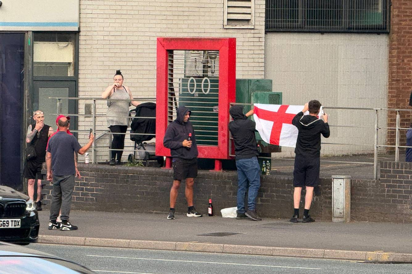 A group of anti-migrant protesters outside Highcross House. Two are putting up an England flag.