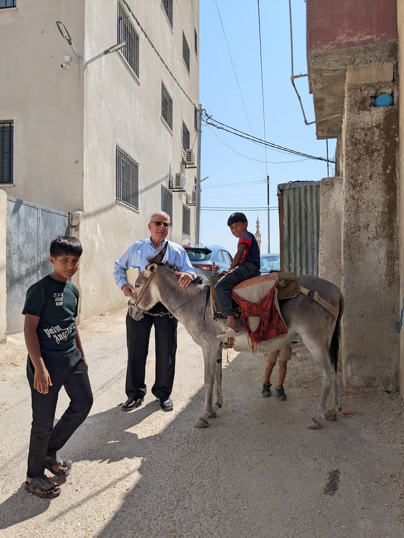 Rizek Housari poses for a photo with young men outside of a refugee camp in Jordan in June 2025.