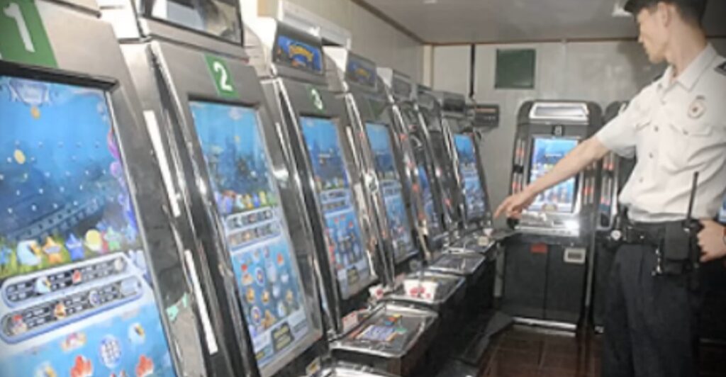 A police officer stands next to several Sea Story (Bada Iyagi) arcade terminals in 2005.