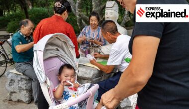 China fertility subsidy: A group of older residents plays cards near a baby in a stroller at a park in Miyun, a district in Beijing, Sept. 18, 2024.