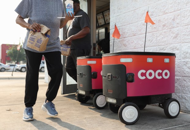 Customers walk past a pair of Coco Robotics autonomous delivery carts parked outside a White Castle restaurant on Chicago's Near West Side, July 31, 2025. (John J. Kim/Chicago Tribune)
