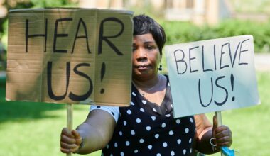 A woman holding a sign calling for people to 'Hear us' and 'Believe us'. Image: Simon Tang/ Women for Refugee Women
