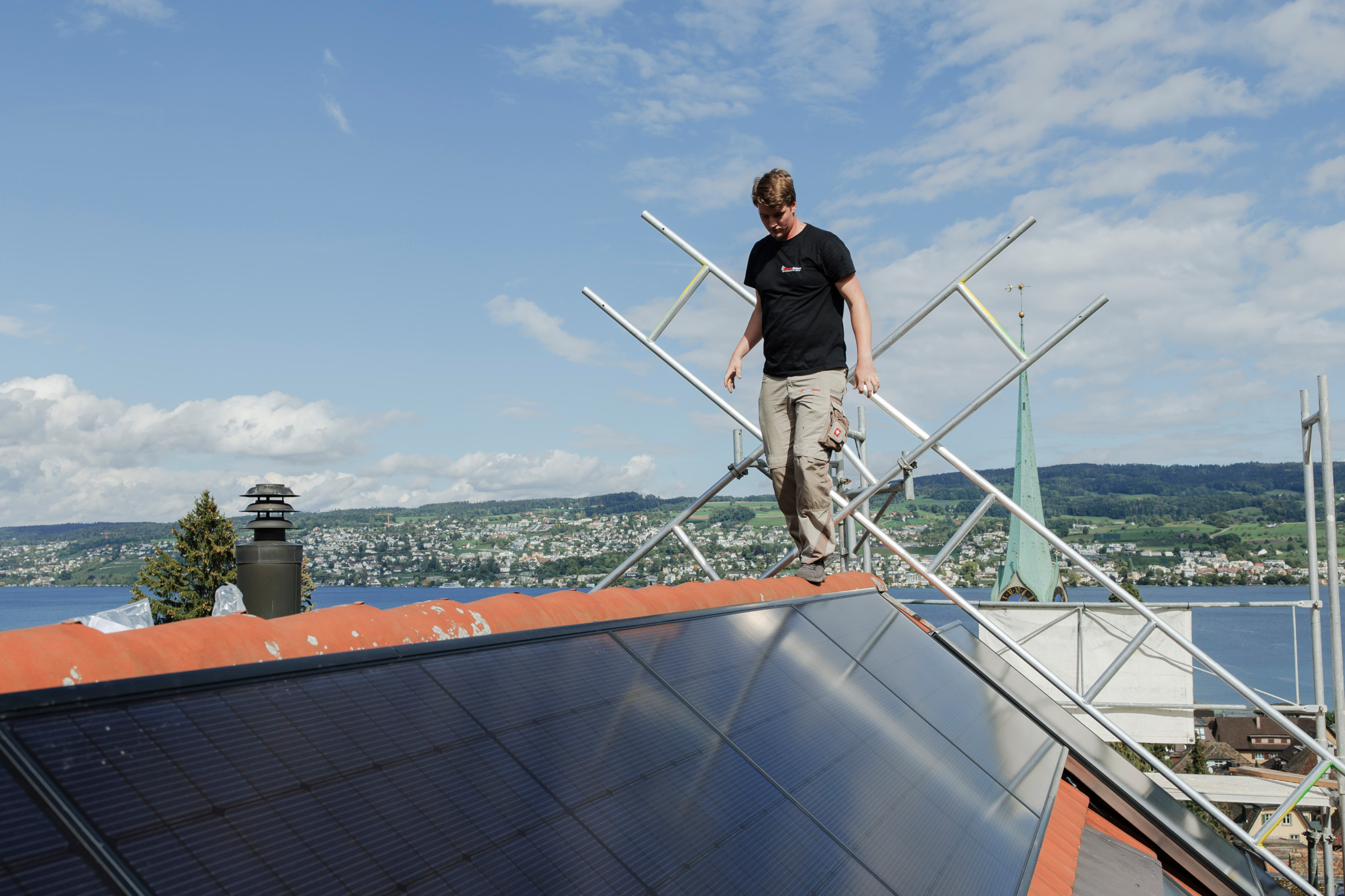 Elektriker und Dachdecker installieren Photovoltaik-Panels auf dem Dach von Herrn Isler in Horgen, mit Blick auf den Zürichsee.