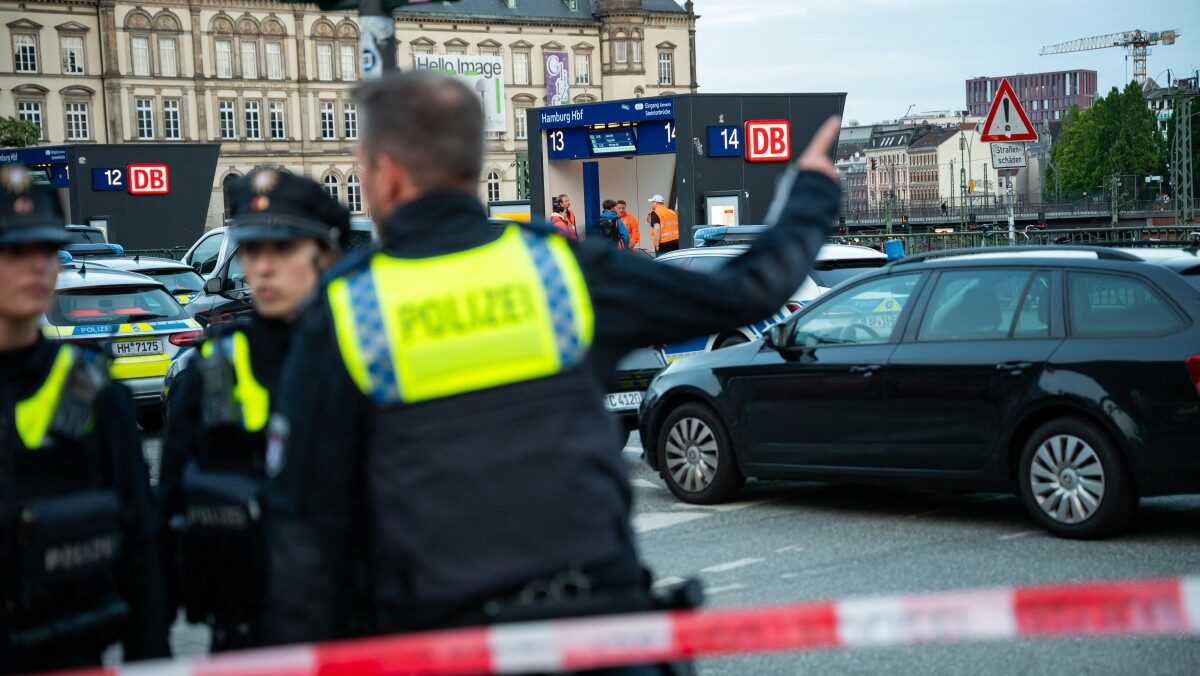Police in hi-vis vests behind crime scene tape