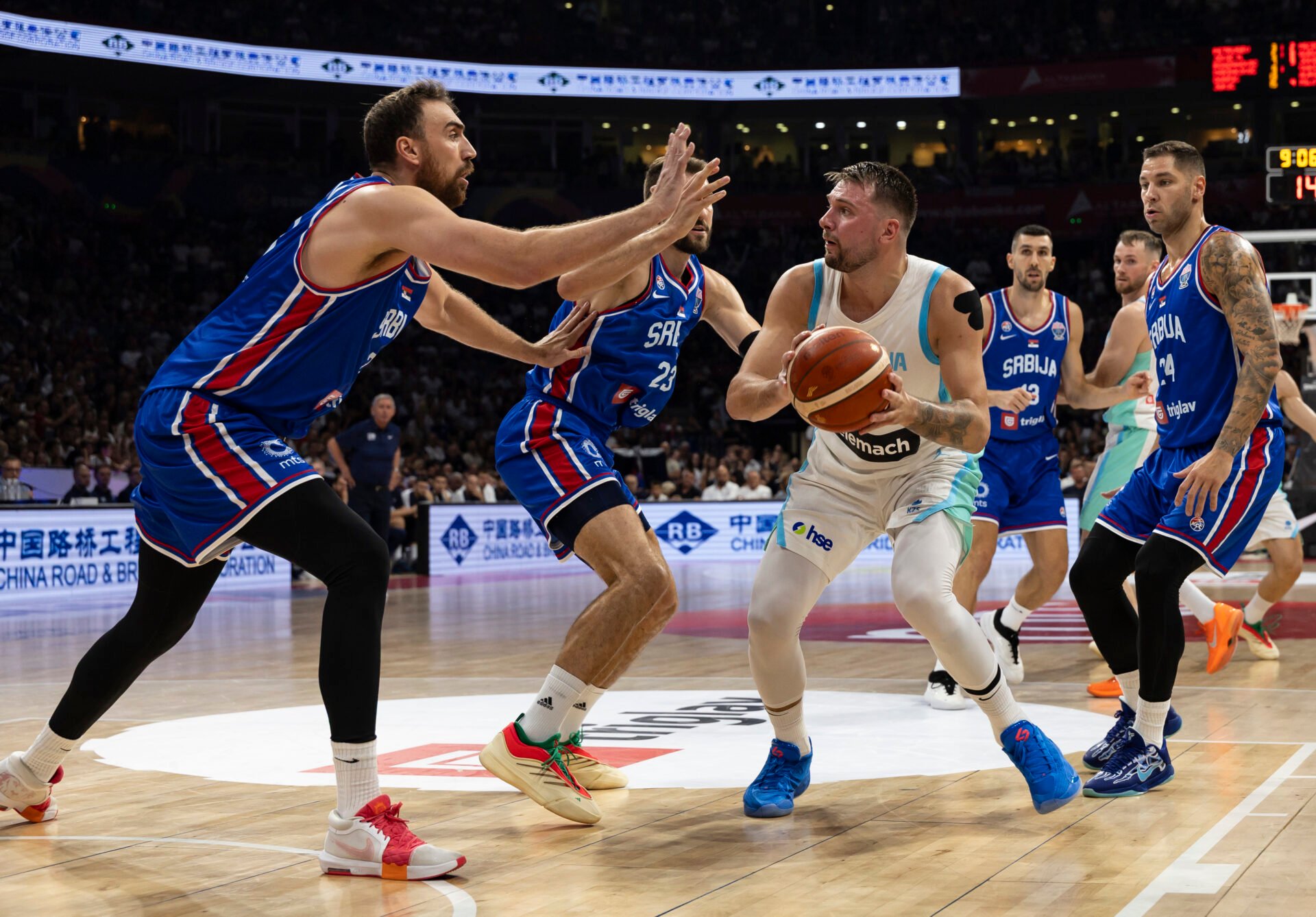 Luka Doncic (C) of Slovenia inis double teamed by Nikola Milutinov (L) and Stefan Jovic (R) of Serbia