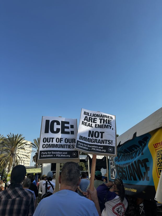 A protester holds two picket signs at a Tuesday, Aug....