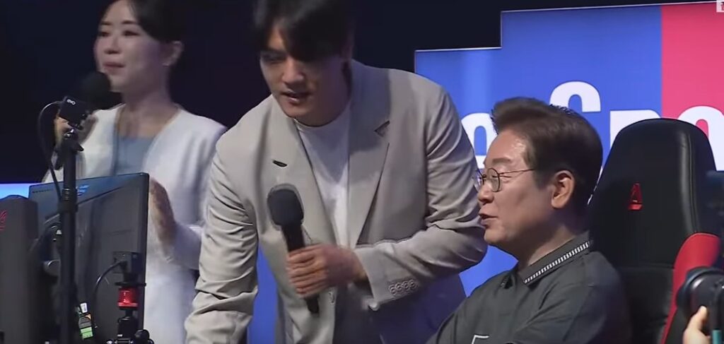 Lee Jae-myung (right, seated) plays a video game on the campaign trail in May this year.