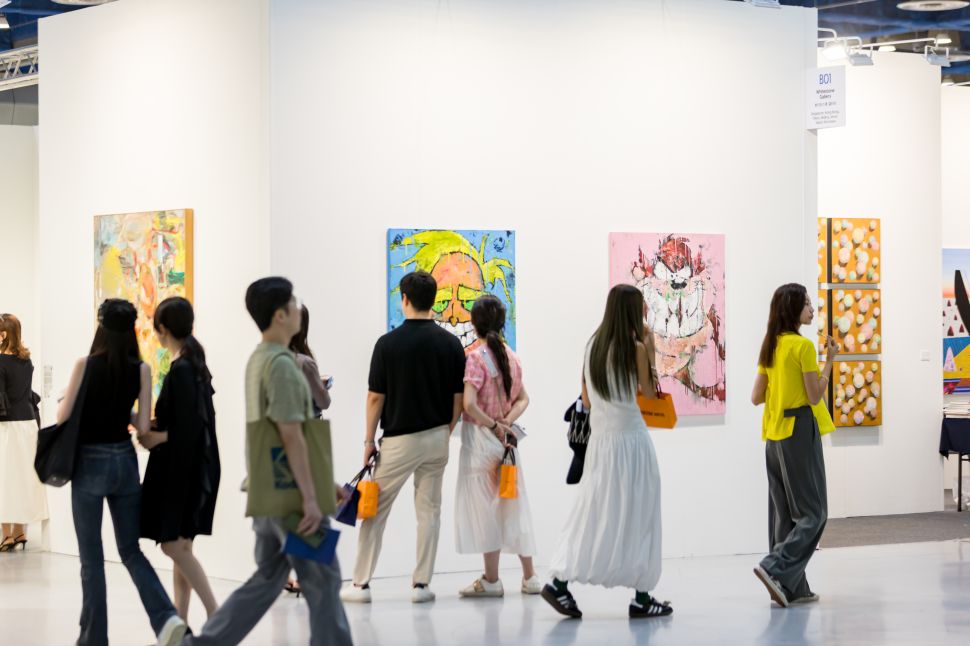 Fairgoers walk past and observe vibrant, large-scale paintings at a Kiaf SEOUL gallery booth.